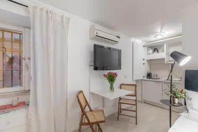 a white living room with a tv and a table and chairs at GuestHost - Basic Studio - 350 m far from Fontana di Trevi in Rome