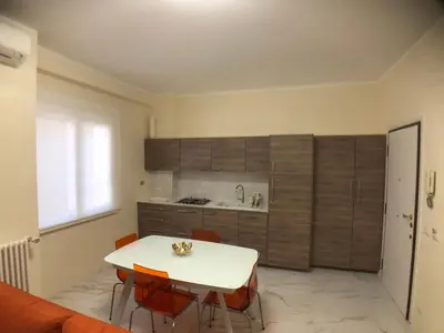 a kitchen with a white table and orange chairs at Maison Carlotta In Vatican in Rome