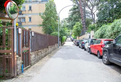a street with parked cars and a fence at Garden City House Roma - Casa con giardino privato in Rome