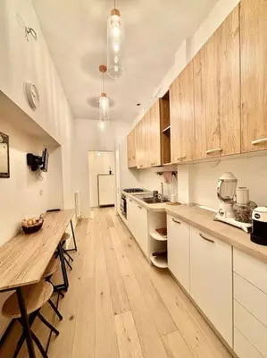 a kitchen with white cabinets and a wooden table at Ovidio Luxury in Rome