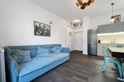 a living room with a blue couch and a kitchen at 15 MIN FROM THE VATICAN Wi-fi and garden in Rome