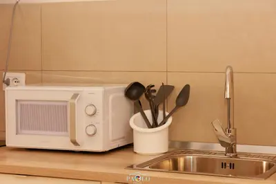 a kitchen counter with a microwave and a cup of utensils at Domus Degli Dei in Rome