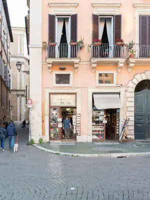 a pink building with a woman walking a dog in a street at Navona Charming Balcony in Rome