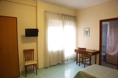a bedroom with a bed and a window with a table and chairs at Casa Piccole Ancelle di Cristo Re in Rome