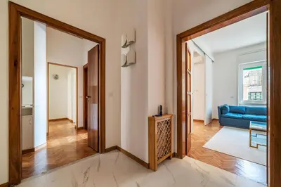 a living room with a blue couch and a doorway at GuestHost - Sapienza & Villa Borghese Comfy Apartment in Rome