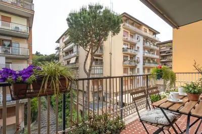 a balcony with a table and potted plants and a building at La Dimora del Vagamondo - ingresso in comune in Rome