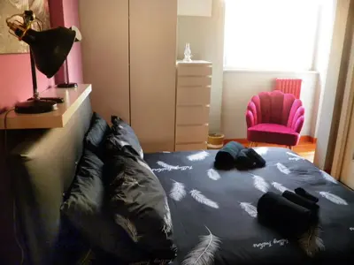 a bedroom with a bed with black sheets and a pink chair at Auditorium Deluxe in Rome