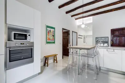 a kitchen with white cabinets and a table with chairs at Colosseo Exclusive House by Premium Suites Collection in Rome