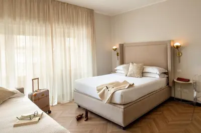 a hotel room with a bed and a suitcase at Daplace - Hotel Gran Torino Suites in Rome
