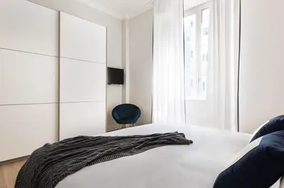 a bedroom with a white bed and a black chair at Idyllia - Elegant central flat in Rome