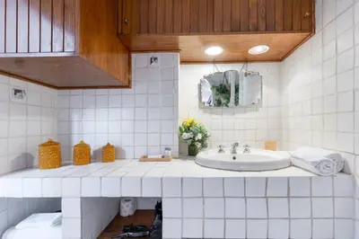 a white tiled bathroom with a sink and a mirror at Rome As You Feel - Librari Penthouse with Terrace in Rome