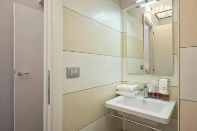 a white bathroom with a sink and a mirror at Arenula Suites in Rome