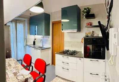a kitchen with white cabinets and red chairs at Un piacevole alloggio turistico in Rome