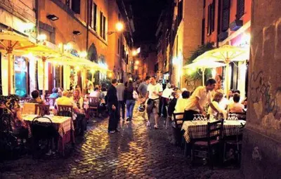 a group of people walking down a street at night at PANTHEON allo SCRIGNO in Rome
