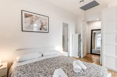 a white bedroom with a bed and a picture on the wall at V E N E R E Apartments in Rome