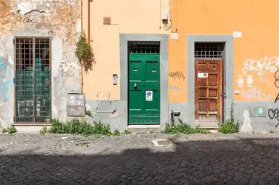 two green doors on the side of a building with graffiti at Trastevere Lovely Apartment in Rome