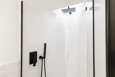 a bathroom with white walls and a glass shower door at Pellegrino 113 in Rome