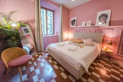 a pink bedroom with a bed and a chair at Telesio Suite in Rome