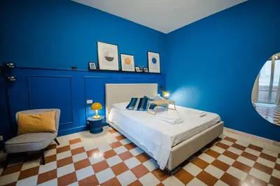 a blue bedroom with a bed and a chair at Telesio Suite in Rome