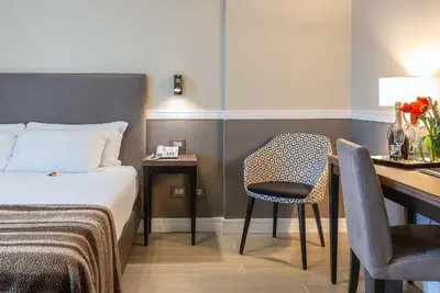 a hotel room with a bed and a desk with a chair at Fragrance Hotel St. Peter in Rome