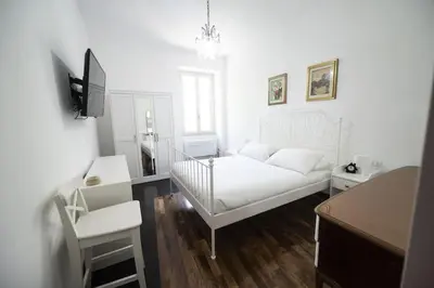 a white living room with a bed and a chair at Testaccio Luminous and Large Apartment in Rome