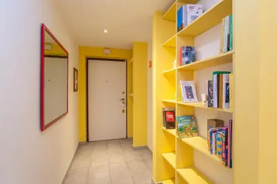 a hallway with yellow walls and shelves with books at Casa Stella in Rome