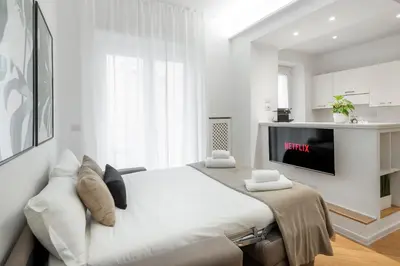 a white bedroom with a bed and a tv at White flat Gallia in Rome