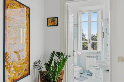 a bathroom with a washing machine and a toilet at Bright Vatican Suite - Garden View Balcony & Full Kitchen in Rome
