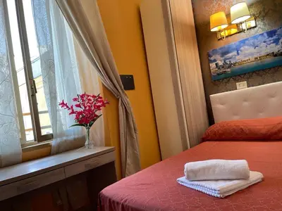 a bedroom with a bed and a vase of flowers on a window at Mille Guest HOUSE in Rome