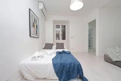 a white bedroom with a bed with a blue blanket on it at Monti Spacious Apartment 2 in Rome