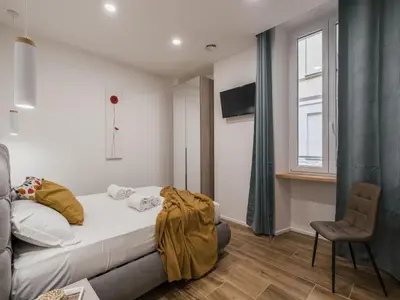 a bedroom with a bed and a chair and a window at The Best Rent - Modern three-bedroom apartment a few steps from the Colosseum in Rome