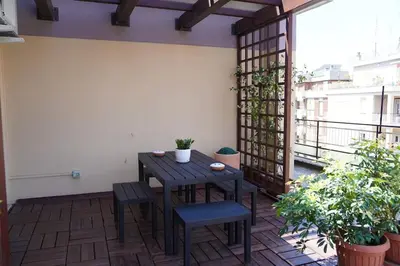 a patio with a wooden table and chairs on a balcony at the sun in rome in Rome