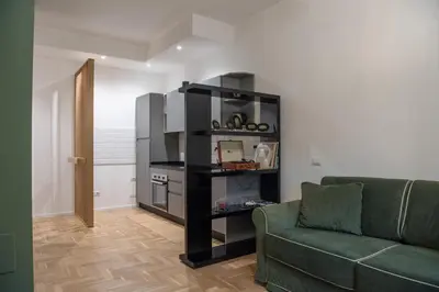 a living room with a green couch and a kitchen at Residenza Clodio Vatican in Rome