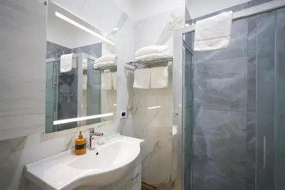 a white bathroom with a sink and a shower at Rohome Stay in Rome