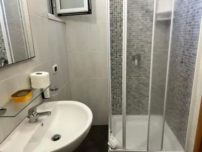 a white bathroom with a shower and a sink at Accommodation Corallo in Rome