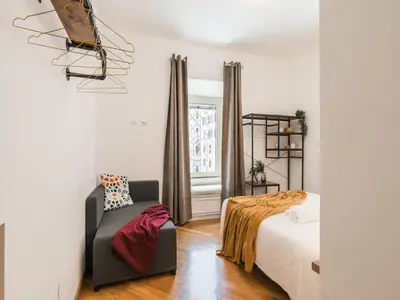 a bedroom with a bed and a chair and a window at The Best Rent - Spacious three-bedroom apartment near the Colosseum in Rome