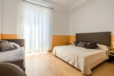 a bedroom with two beds and a large window at La Maison Royale in Rome