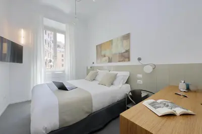 a bedroom with a bed and a desk with a book at YCH-Montebello - Rooms in Rome
