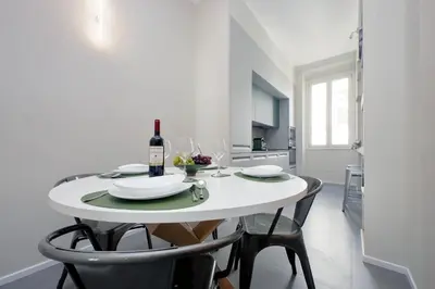 a white dining room table with a bottle of wine at YCH-Montebello - Rooms in Rome