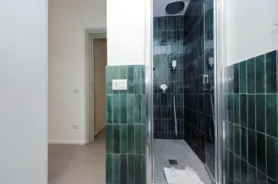 a bathroom with a shower with green tiles at YCH-Montebello - Rooms in Rome