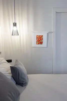 a white bedroom with a bed with a pillow and a light at La Dolce Vita - Old Testaccio Authentic District in Rome