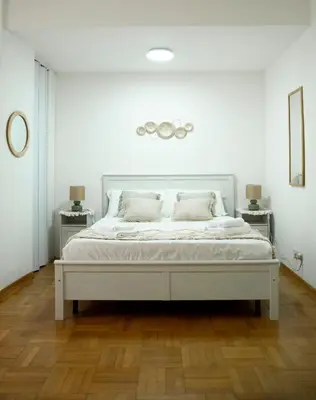 a white bed in a white room with two tables at Shabby Roman Studio- ai fori Imperiali in Rome