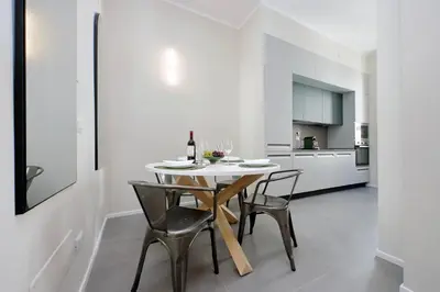 a white dining room with a table and chairs at Youcomehere - Montebello in Rome