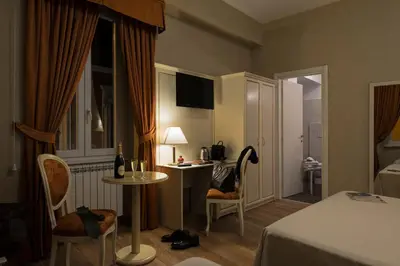 a hotel room with a bed and a table and chairs at Relais Bocca di Leone in Rome