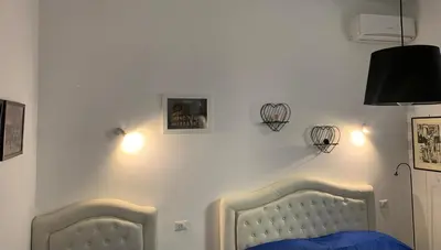 two beds in a bedroom with lights on the wall at casa Nannarè in Rome
