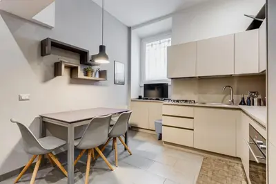 a kitchen with white cabinets and a table and chairs at casa Nannarè in Rome