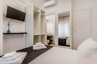 a white bedroom with a bed and a tv on the wall at Casa Roma B&B in Rome