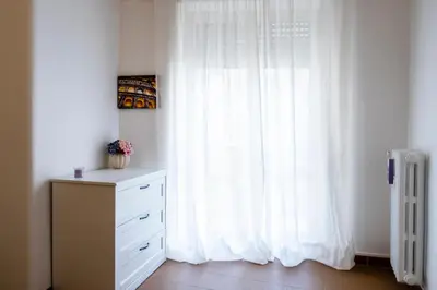 a white curtain in a room with a dresser and a window at Appartamento Appio Latino in Rome