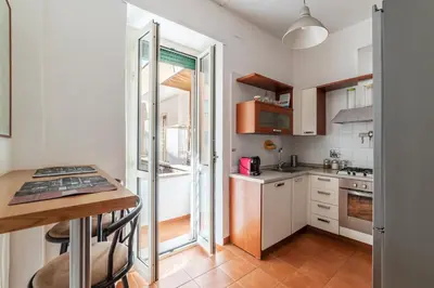 a small kitchen with white cabinets and a table at GuestHost - Rione Prati Comfy Apartment in Rome