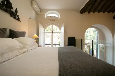a bedroom with a large white bed with two windows at Your Prestigious Penthouse at the Spanish Steps in Rome